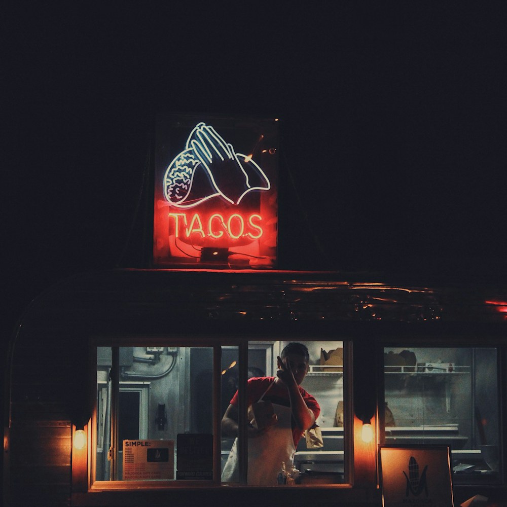 Ventanilla de la taquería de noche con el letrero de neón